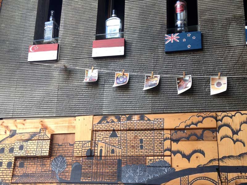 Dekorasi kafe dengan mural dan pajangan foto, bendera dan botol minuman